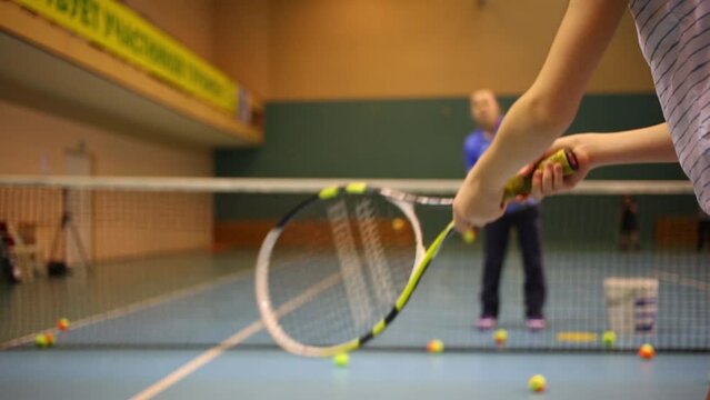 Hands of girl learning to beat off balls. Teacher and net out of focus