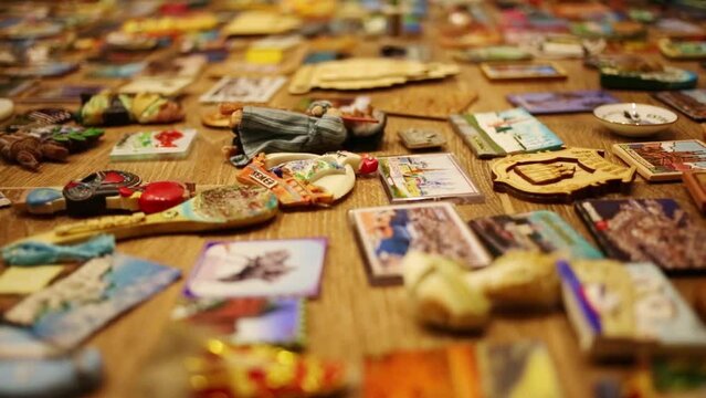 Many bright refrigerator souvenir magnets on wooden floor