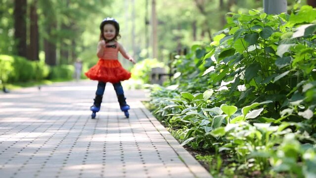Little girl in skirt roller-blades and brakes in park