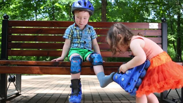 Little cute boy sits on bench and girl helps to him in park