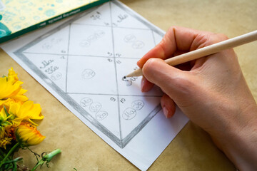 A woman's hand fills in an astrology chart of Jyotish astrology of ancient India