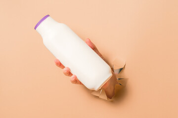 Cool view on shampoo, hair conditioner or body lotion bottle in hands in beige background. Bottles...
