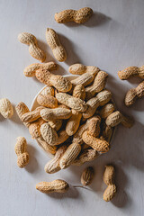 Top view of scattered in shell peanuts on plate and white background