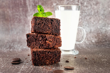 Stack of chocolate brownies with milk glass on dark stone background, homemade bakery and dessert