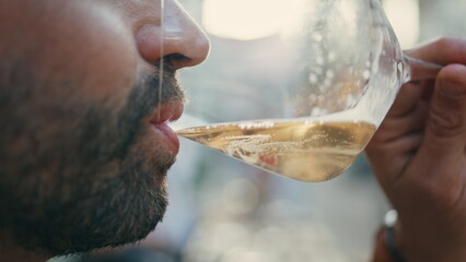 Bearded guy sipping wineglass at city street closeup. Man face drinking alcohol 