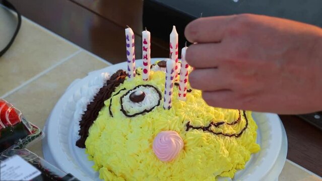 Hands setting candles in cake in form of smiling face
