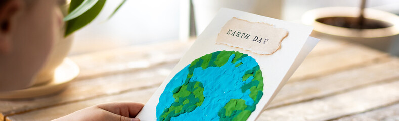 Banner. Concept of raising awareness about the environmental issues on the Earth day. Kid doing craft postcard with planet on it. Promoting sustainable lifestyle, environment protection - obrazy, fototapety, plakaty