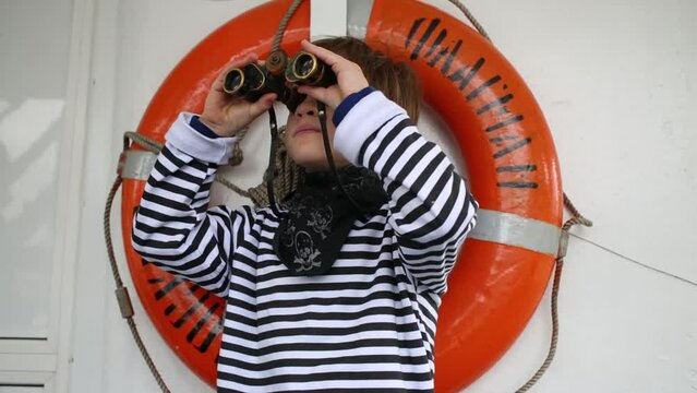 Boy stands in the background of a life buoy on the boat Flagman