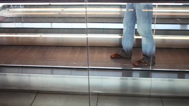 Male legs in jeans walking backwards by moving walkway