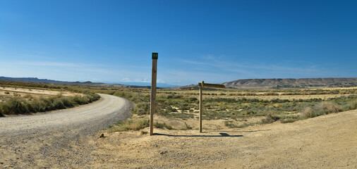 vu panoramique sur route dans le désert de Navarre en Espagne  avec ciel bleu et panneau d'indication en bois