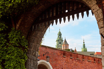 An old vintage metal gate with an archway to the old Zamek Krolewski na Wawelu castle in the center...