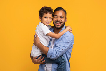 Fototapeta premium Happy black father lifting his little son and hugging
