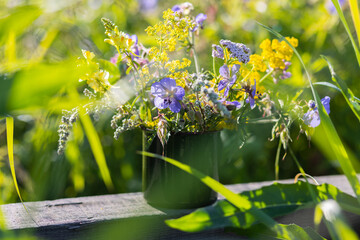 Bouquet of bright colourful summer wildflowers in a green metal mug on wooden background. Sunny morning. Baikal lake, Siberia © ArtSys
