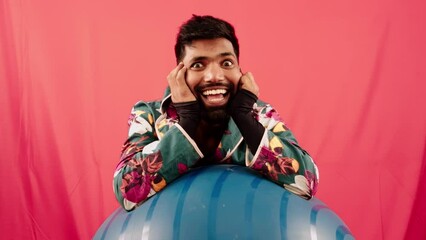 man thinking laughing posing against red background on exercise ball