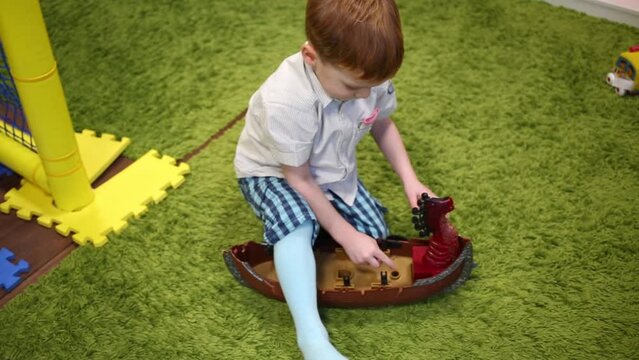 Boy playing with plastic Viking ship on green carpet