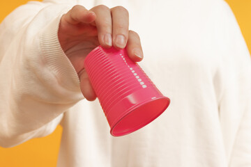 A hand tipping a red plastic cup.