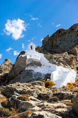 Theologaki Chapel on a hill with a blue sky filled with a white cloud. Naxos Island. Cyclades of Greece. Vertical framing. - 717170761