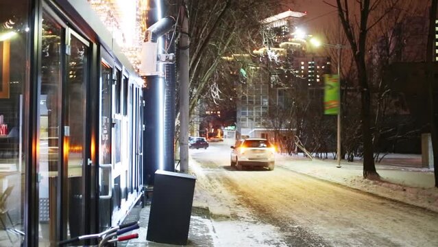 White car goes away in winter night, blinking lights