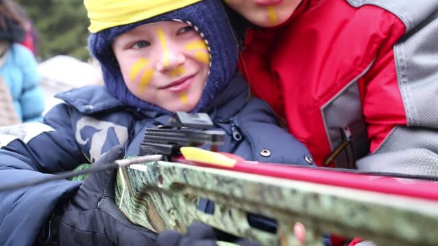 Little boy learns to shoot crossbow by means adult