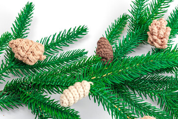 Cozy crocheted pine cones on evergreen Christmas tree branch. Creative handmade decor, craft mood