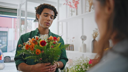 Joyful customer present flower to seller lady in plant store. Romantic concept.