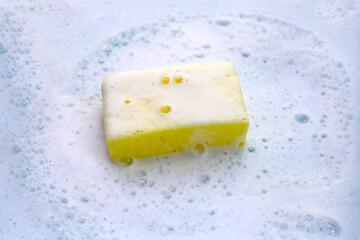 Cleaning sponge in foam of dishwashing liquid. Washing dishes concept