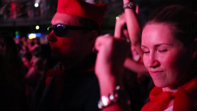 Two woman and man in sunglasses dance among other people