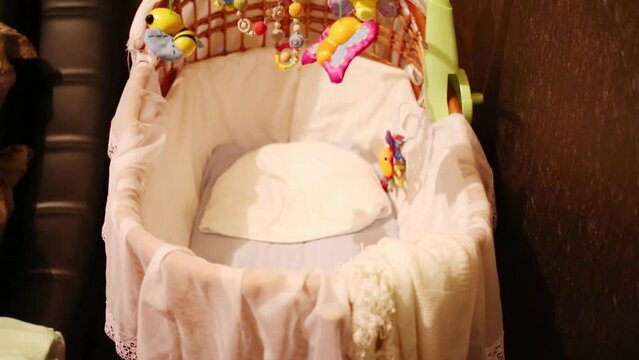 Closeup of small empty cot with attached toys in room