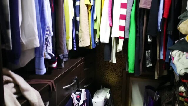 Wardrobe with dresses and clothes and sewing machine on floor