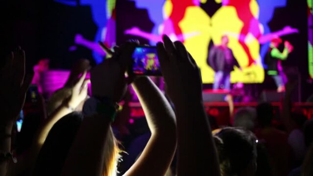 Hands hold phone, that shoots video during performance in night club