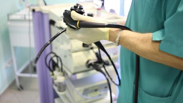 Doctor in uniform and rubber gloves holding an endoscope