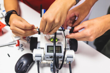 Group of diverse children kids with robotic vehicle model, close-up view on hands, science and...
