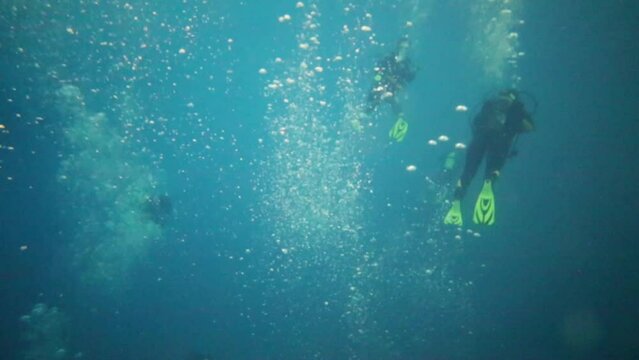 Scuba divers submerged in pool with many bubbles in deep pool