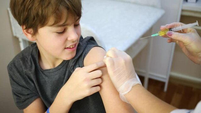 Female doctor prepares arm of boy to make injection.