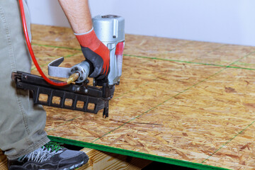 New home with installation wooden plywood to floor using air nail gun