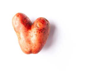 Heart-shaped raw potato. Funny vegetable on white background.