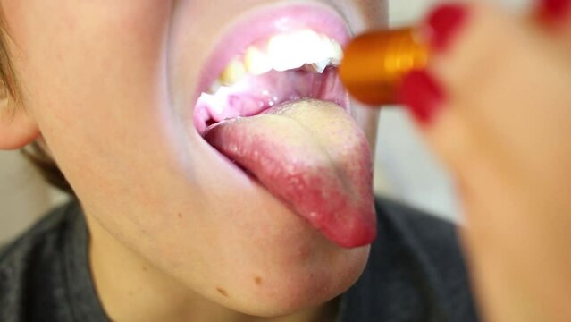 Doctor examines throat of boy illuminating by flashlight.