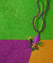 Mardi Gras beads with Fleur de lis, in glittering green, purple, and gold. Sparkling festive background for Mardi Gra in traditional colors. - obrazy, fototapety, plakaty