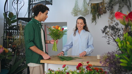 Happy businesswoman florist sell flower composition. Curly hair man buy gift.