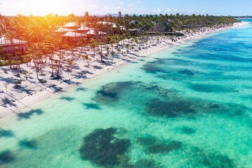 Sunset or sunrise on tropical beach with resorts, palm trees and caribbean sea. Dominican Republic. Aerial view - obrazy, fototapety, plakaty