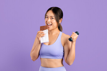 Young asian woman enjoys chocolate while working out
