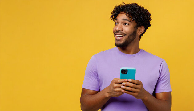 Oung Man Of African American Ethnicity Wear Purple T-shirt Casual Clothes Hold In Hand Use Mobile Cell Phone Look Aside On Area Isolated On Plain Yellow Background Studio Portrait. Lifestyle Concept