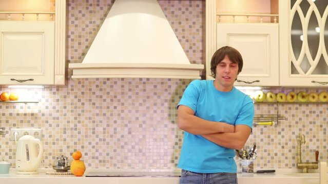 Young man standing in the kitchen with arms crossed