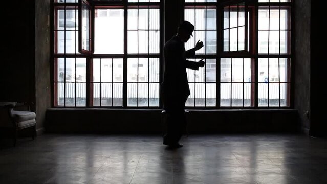 Silhouette of man in black suit and hat dancing tango