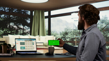 Rich financial investor using greenscreen on mobile device, trying to develop global business from...