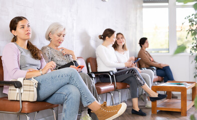 Woman is sitting in the lobby of a large company, waiting for her turn to see a specialist in office