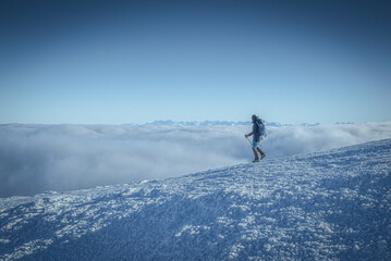 Turysta nad chmurami schodzący z Babiej góry, widok na Tatry