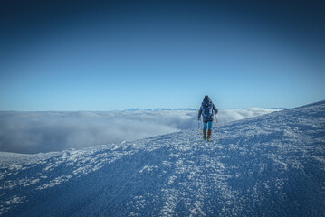 Turysta nad chmurami schodzący z Babiej góry, widok na Tatry