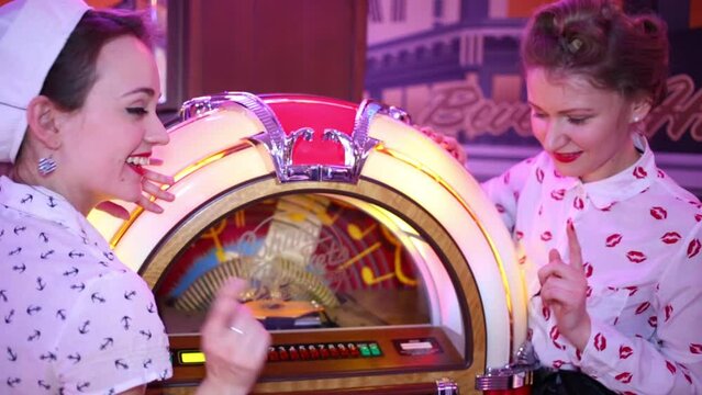 Two girls stand near Jukebox at Retro Beauty Day in Beverly Hills Diner