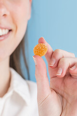 Woman holding orange gummy vitamin in hand
